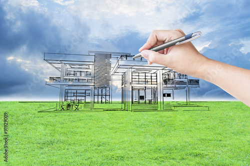 architect hand drawing a house on the grass field and sky background