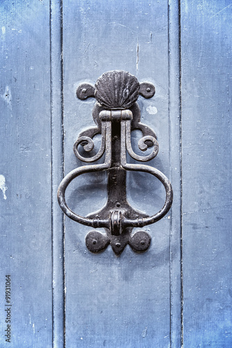 Old vintage door knocker on an old blue wooden door