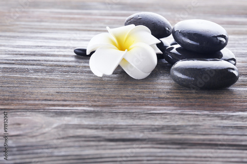 Wet spa stones with flower on wooden background