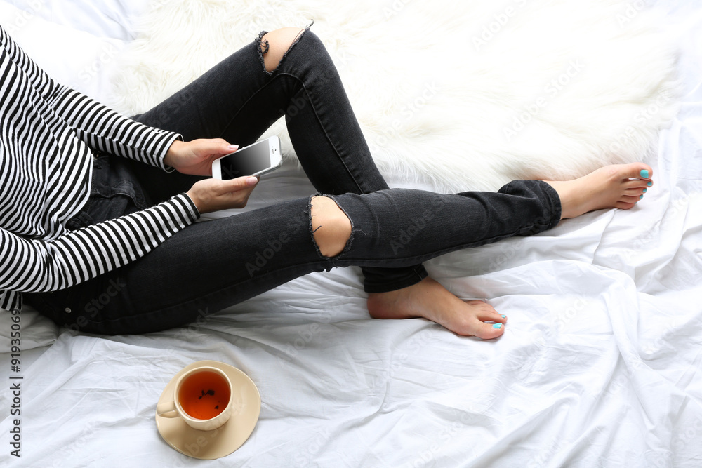 Woman on the bed with phone and cup of coffee, top view point