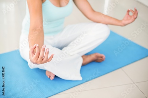 Pregnant woman sitting in lotus pose on exercise mat