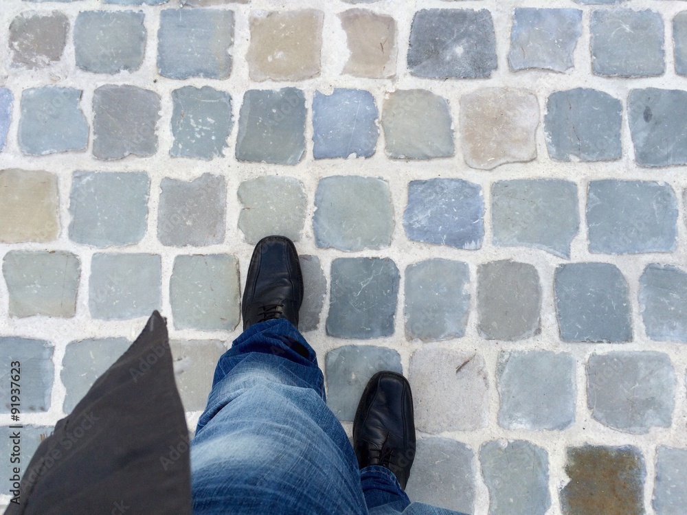homme qui marche dans une rue pavée homme qui marche dans une rue pavée