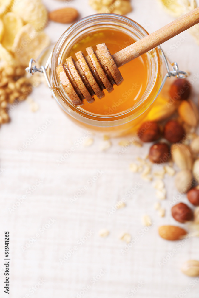 Fototapeta premium Honey in glass jar and nuts. Country breakfast concept