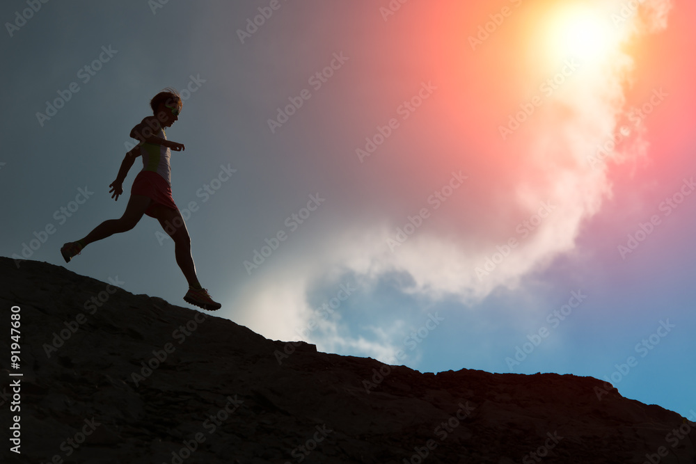 Woman runs on the ridge with colorful sun