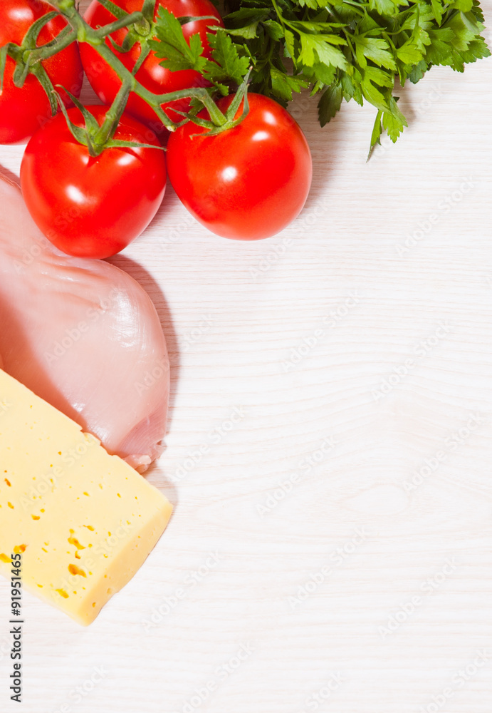 Food background of fresh chicken breast, cheese and tomato at the wooden board with copy space Food background of fresh chicken breast, cheese and tomato at the wooden board with copy space