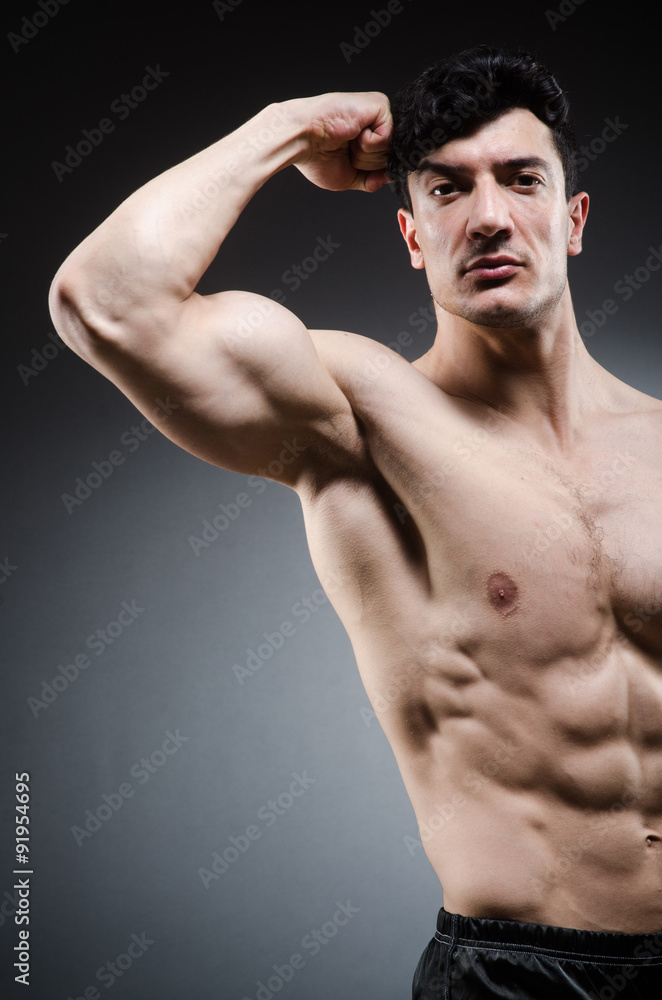 Fototapeta premium Muscular man posing in dark studio