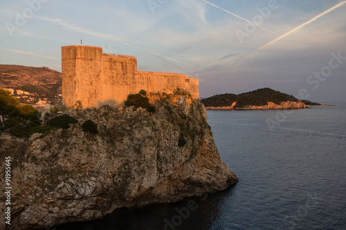 View of Fort Lovrijenac (St. Lawrence Fortress) on top of a steep cliff in Dubrovnik, Croatia, at sunset.