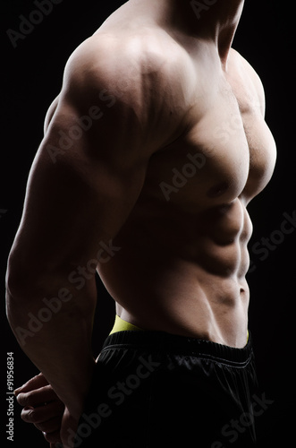 Muscular man posing in dark studio