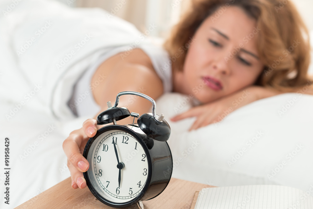Young sleepy woman trying to turn off the alarm clock Young sleepy woman trying to turn off the alarm clock