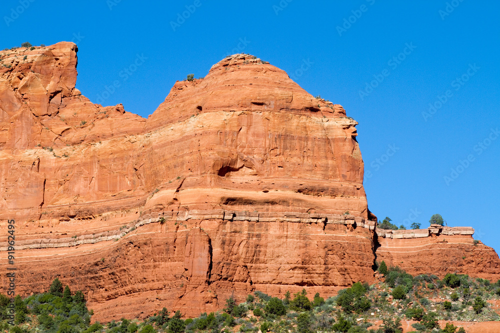 Fototapeta premium Massive red-rock cliffs, pines, and blue sky along Schnebly Hill Road near Sedona, Arizona