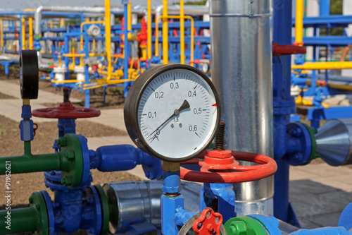 Pressure meter and red faucet with steel yellow pipe in natural gas treatment plant in bright sunny summer day photo