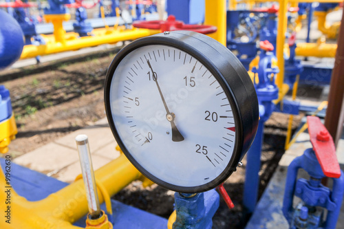 Pressure meter and red faucet with steel yellow pipe in natural gas treatment plant in bright sunny summer day photo