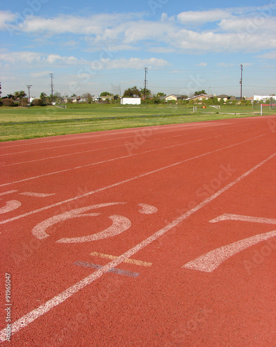 orange athletic track with green field in background