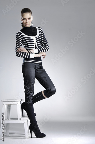 beautiful girl is in fashion style with wooden cube standing in studio