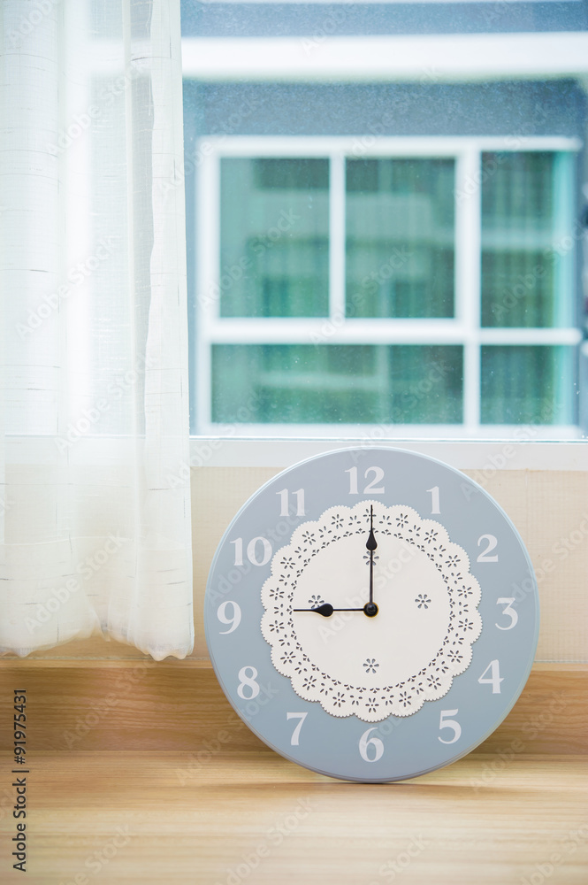 Clock showing 9 o'clock near a window
