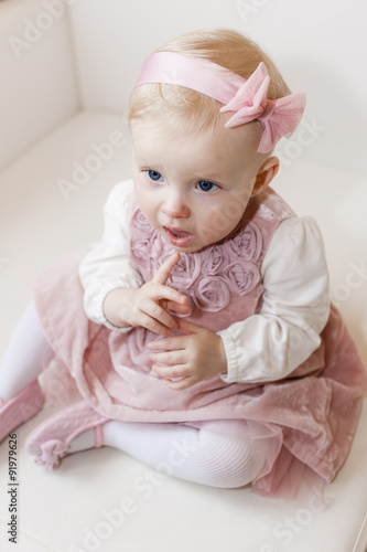 portrait of sitting toddler girl wearing pink dress