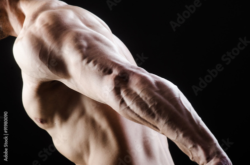 Muscular man posing in dark studio