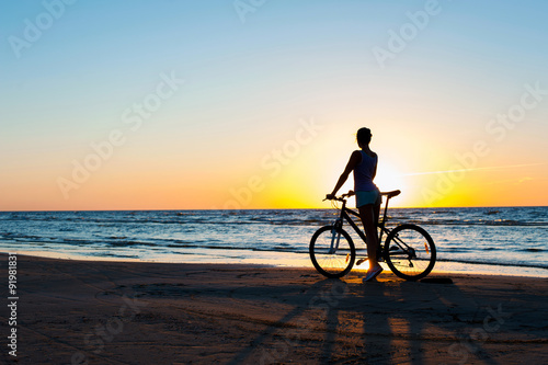 Moment in time. Woman cyclist silhouette on multicolored sunset