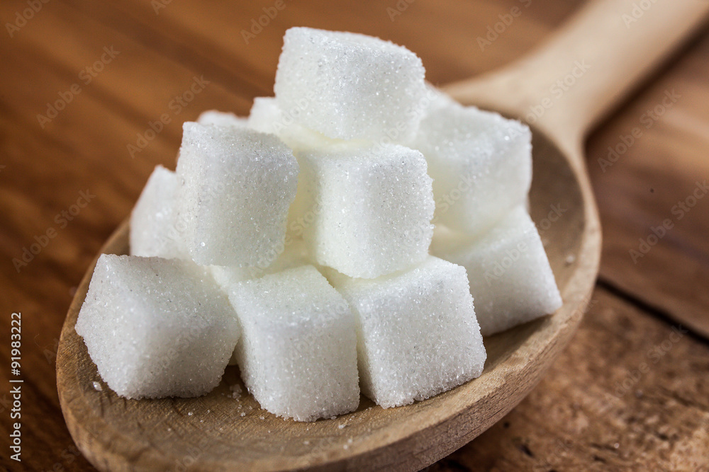 Sugar Cubes on Wooden Spoon over Wooden Background Sugar Cubes on Wooden Spoon over Wooden Background