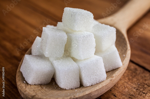 Sugar Cubes on Wooden Spoon over Wooden Background