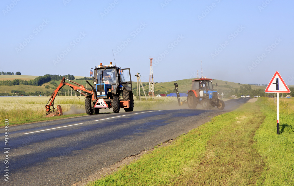 Fototapeta premium Tractor mows grass on the side of road.