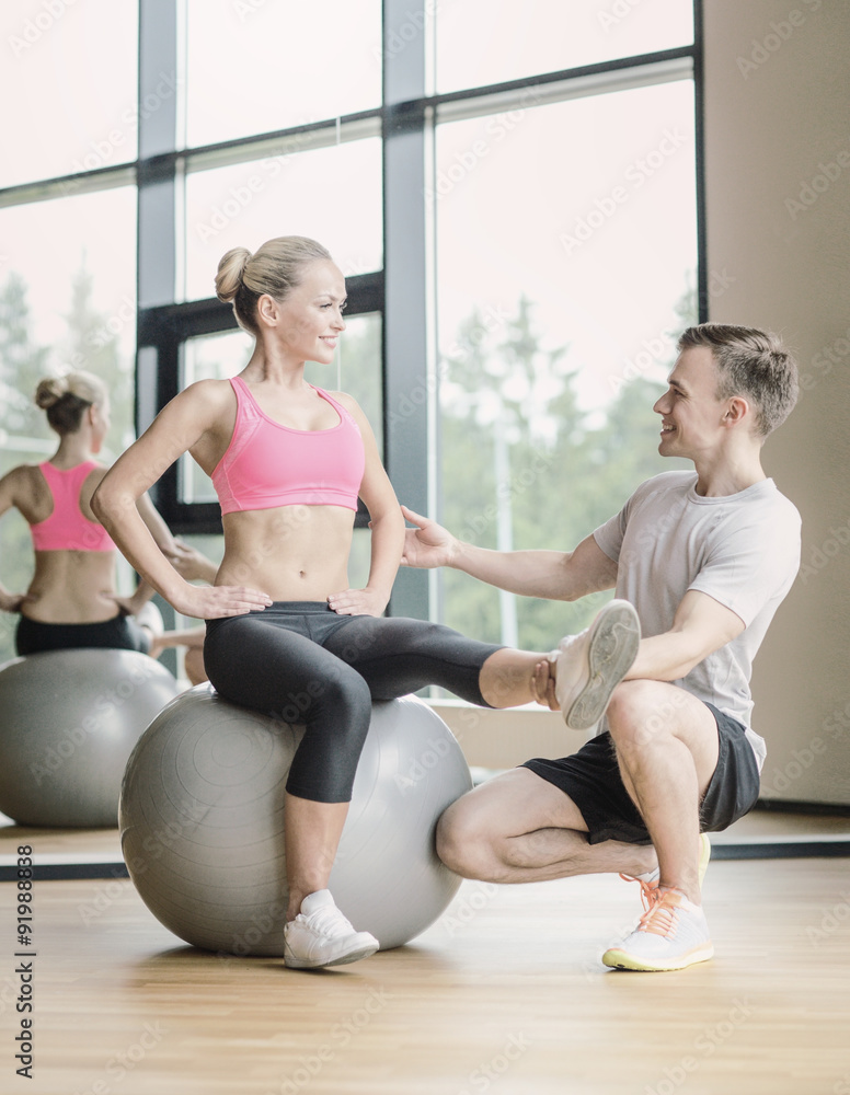 smiling man and woman with exercise ball in gym