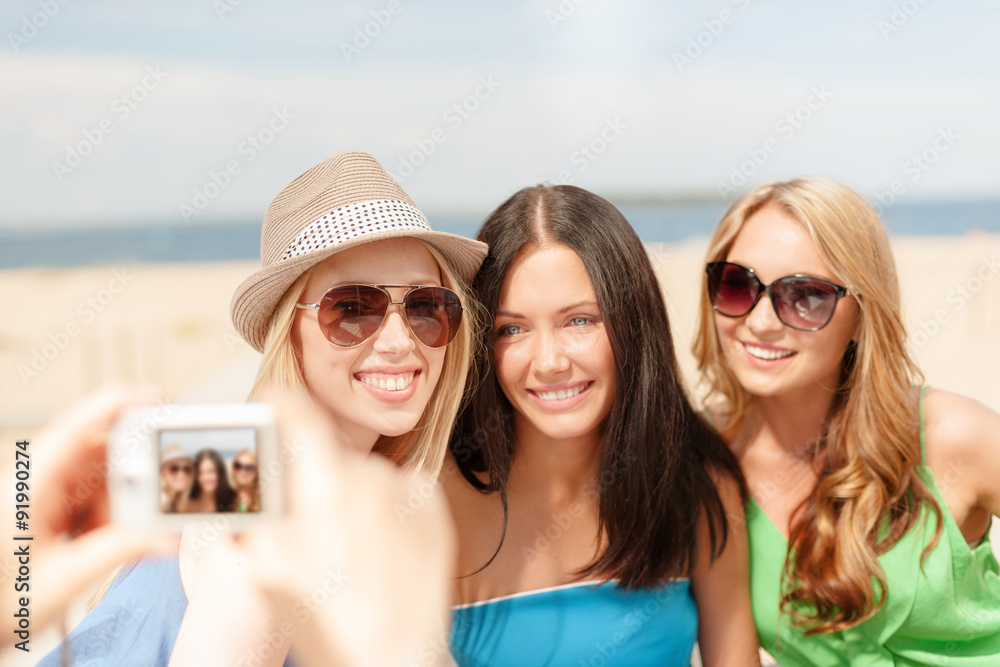 girls taking photo with digital camera in cafe