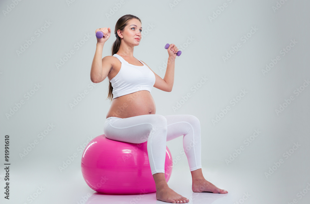 Woman sitting on a fitness ball and workout with dumbbells Woman sitting on a fitness ball and workout with dumbbells