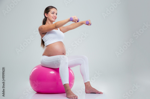 Woman doing exercises with dumbbells on a fitness ball
