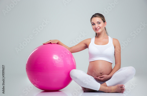 Pregnant woman sitting on the floor with fitness ball © Drobot Dean