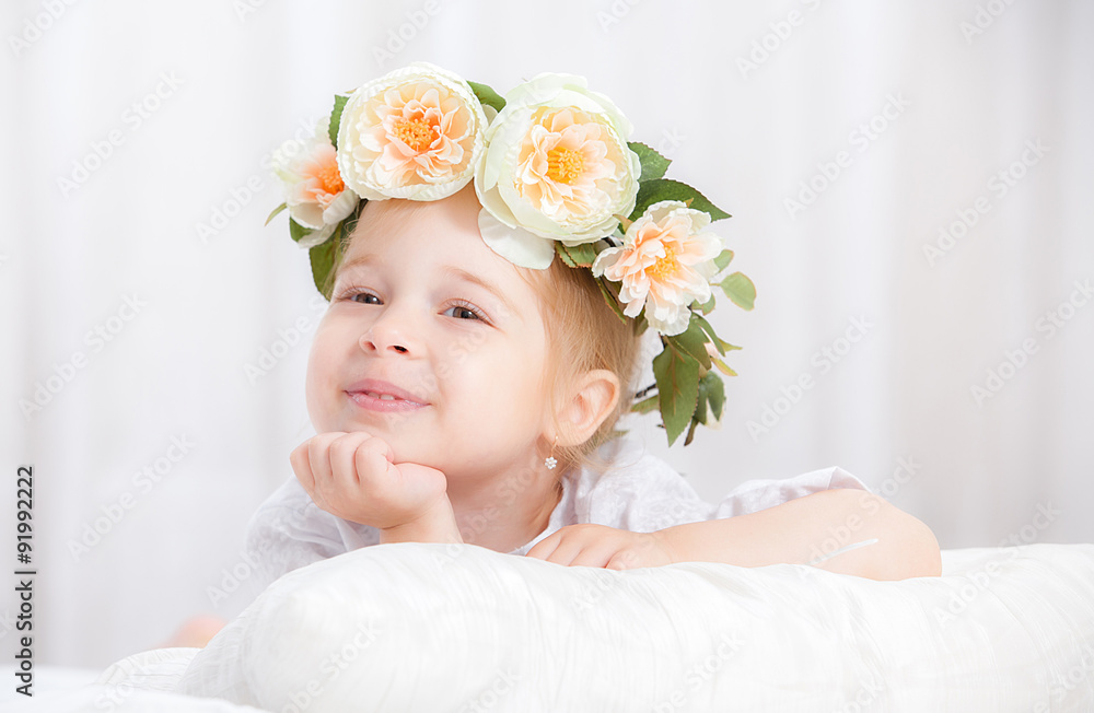 happy little girl with a wreath on the head on a bed happy little girl with a wreath on the head on a bed