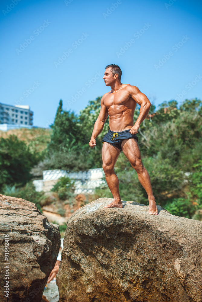 Man Athlete stands on a rock by the sea against the sky Man Athlete stands on a rock by the sea against the sky