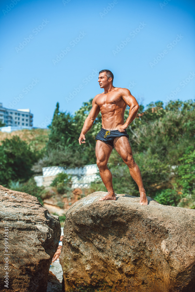 Man Athlete stands on a rock by the sea against the sky Man Athlete stands on a rock by the sea against the sky