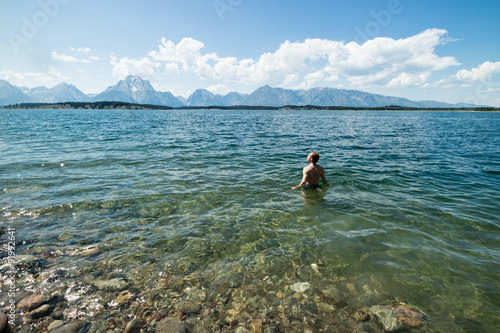 Man relaxing in clear lake looking at the Teton mountain range, part of the Grand Teton National Park, USA