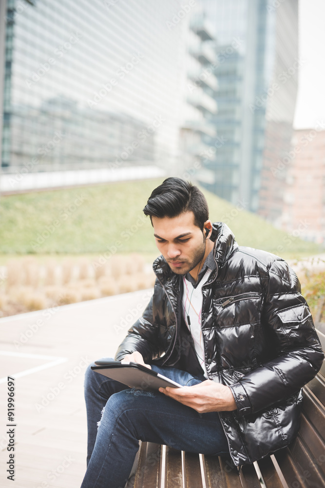 Young handsome indian contemporary businessman seated on a bench