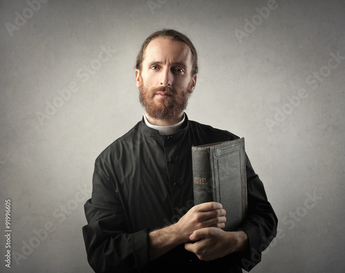 Obraz na plátne Priest holding a Bible