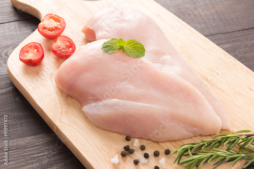 Raw chicken breast fillets on wooden background.