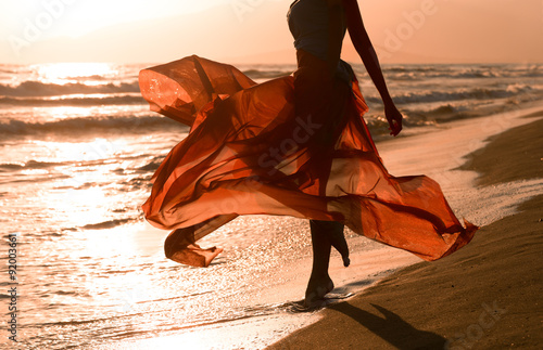 Beautiful woman with flying red dress, beach