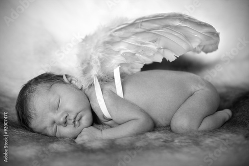 Black and white photo of a new born baby wearing angel wings.