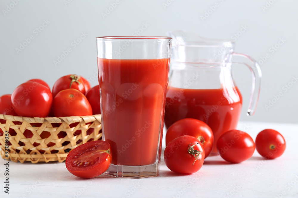 Fresh red tomatoes in basket and tomato juice in glass and jug o Fresh red tomatoes in basket and tomato juice in glass and jug o