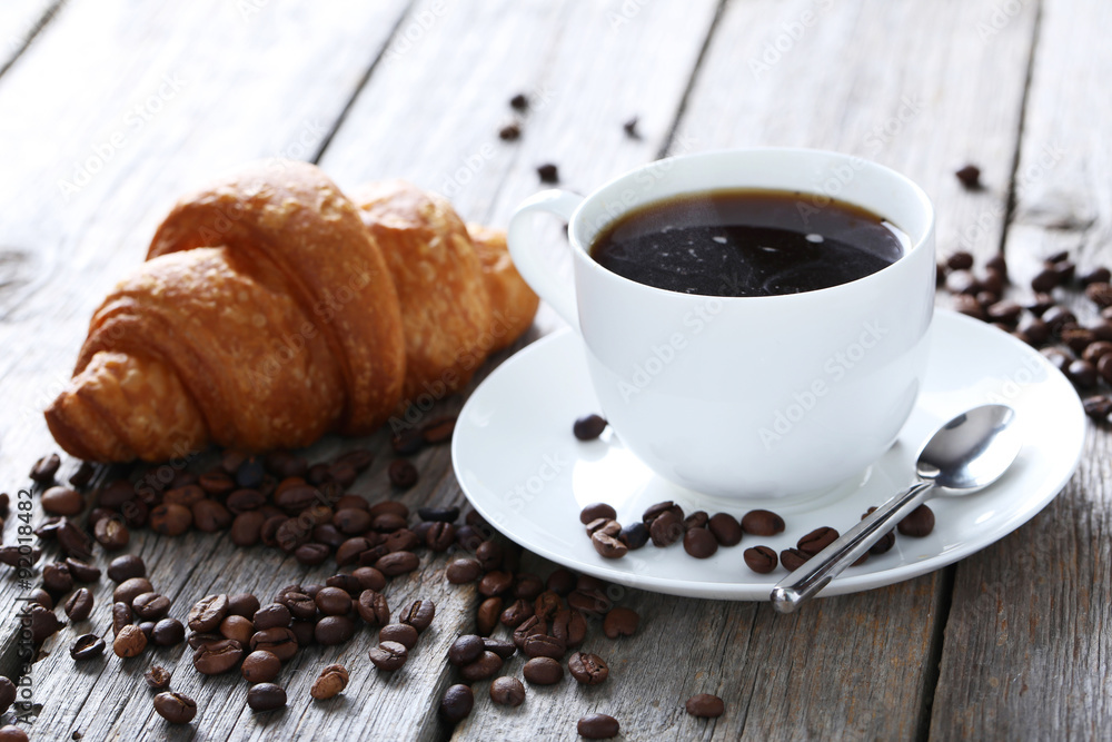 Delicious croissants with cup of coffee on grey wooden backgroun Delicious croissants with cup of coffee on grey wooden backgroun