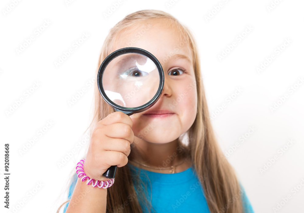 Smiling girl looking through a magnifying glass Smiling girl looking through a magnifying glass