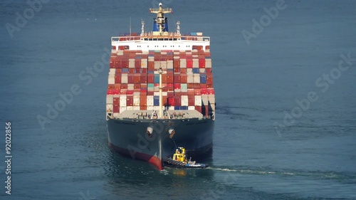 Tug Boats Pushing Freighter Around At Sea