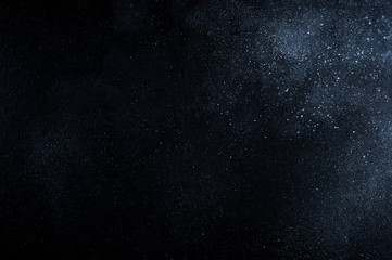 Dust powder explosion particles on dark blue black background