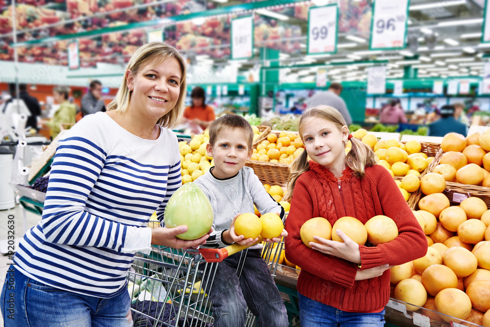 Mother and children with pineapples in fruit department in super