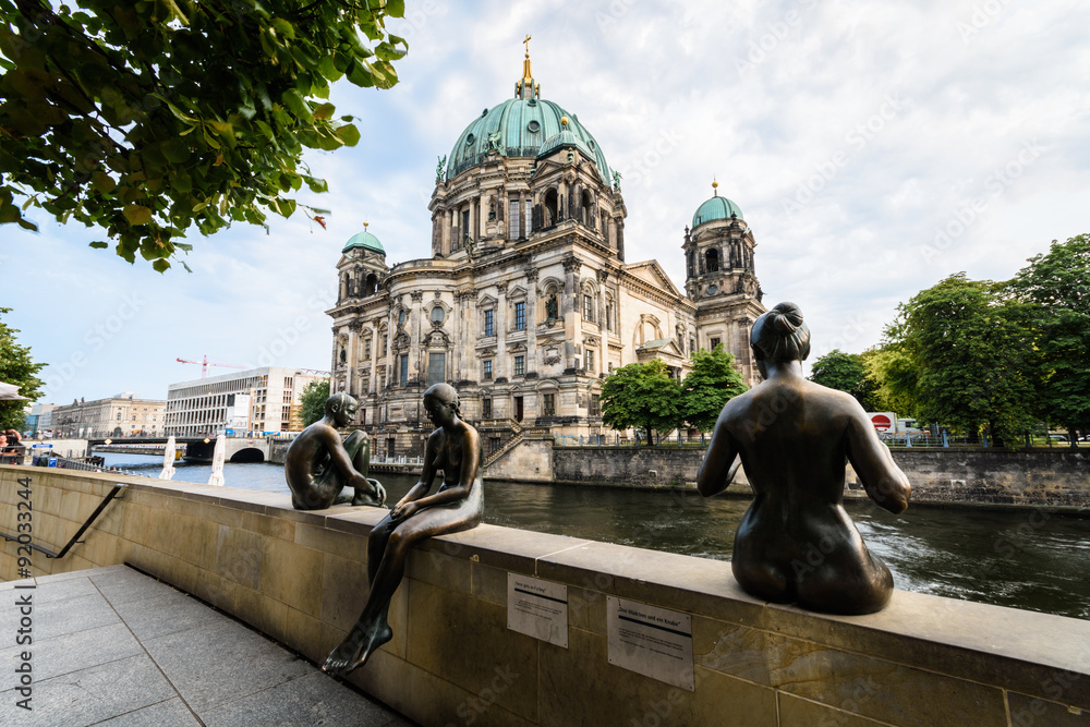 3 statues sit at the riverside. In the background is the Berliner Dom. - obrazy, fototapety, plakaty 