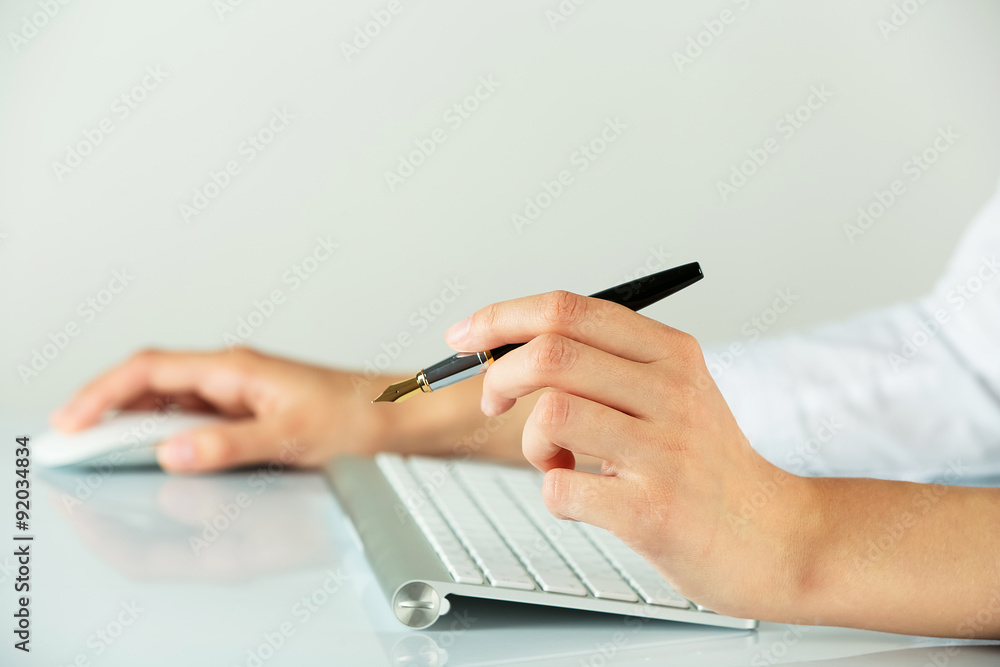 Female hands holding pen and computer mouse on light background Female hands holding pen and computer mouse on light background