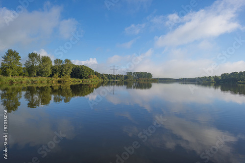 Fototapeta Naklejka Na Ścianę i Meble -  The shore of a hazy sunny lake in autumn
