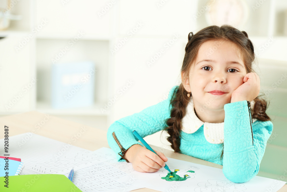 Cute little girl doing her homework, close-up, on home interior background Cute little girl doing her homework, close-up, on home interior background