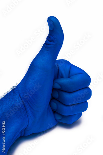 A young man' with blue hand is displaying a thumbs up, indicating that he likes or approves of something